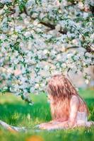 Adorable little girl in blooming apple tree garden outdoor photo