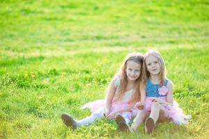 Adorable little girls on spring day outdoors sitting on the grass photo