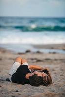 papá con su pequeña hija se acuesta en la playa al atardecer y disfruta del tiempo juntos foto