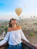 mujer feliz durante el amanecer viendo globos aerostáticos desde una canasta en el cielo en capadocia, turquía foto