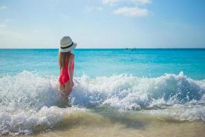 Adorable little girl playing in shallow water at exotic beach photo