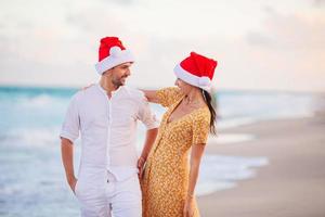 pareja feliz de navidad en sombreros de santa en vacaciones en la playa foto