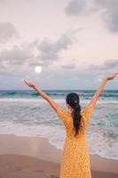 Happy woman enjoying beautiful sunset with big full moon on the beach photo