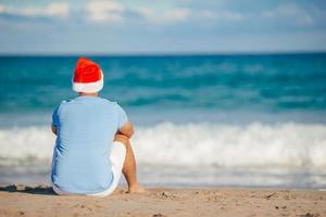 joven con sombrero de santa en vacaciones de navidad en la playa foto