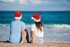 Christmas happy couple in Santa hats on beach vacation photo