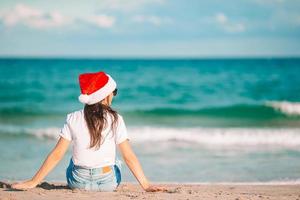 Mujer joven con gorro de Papá Noel en Navidad vacaciones en la playa foto