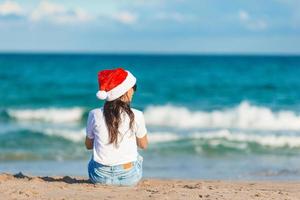 Mujer joven con gorro de Papá Noel en Navidad vacaciones en la playa foto