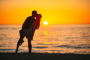 Young family enjoy honeymoon at sunset on the beach photo