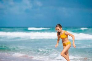 Little happy girl splashing and running in clear turquoise water photo