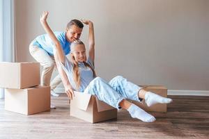 Family of dad and his teen girl have fun in their new home with cardboard boxes. Family enjoy their moving day photo