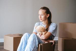 Happy adorable girl with cardboard boxes in new house at moving day photo