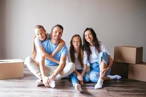 Happy family with two daughters with cardboard boxes in new house at moving day photo