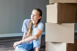 Happy adorable girl with cardboard boxes in new house at moving day photo