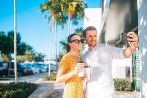 pareja joven con café para ir a la calle en la ciudad de verano tomando selfie foto