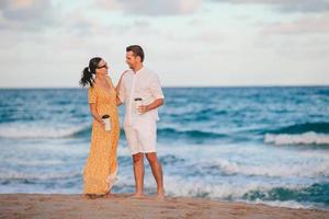 Young couple on the beach waking and enjoy coffee to go photo