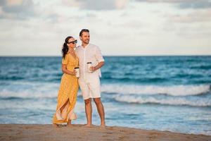 pareja joven en la playa despertando y disfrutando de un café para llevar foto