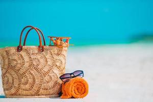 Beach accessories - bag, straw hat, sunglasses on white beach photo