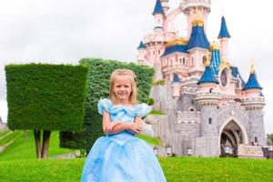 Little adorable girl in beautiful princess dress at fairy-tale park photo