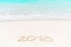 2018 handwritten on sandy beach with soft ocean wave on background photo