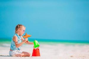 Adorable little girl playing with beach toys on white tropial beach photo