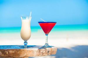 Two cocktails, pina colada and strawberry margarita on white sand beach photo