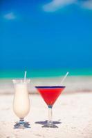 Two cocktails, pina colada and strawberry margarita on white sand beach photo