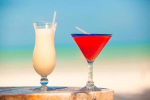 Two cocktails, pina colada and strawberry margarita on white sand beach photo