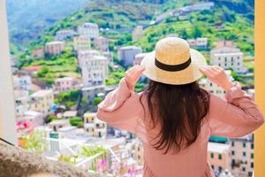 hermosa mujer con una vista increíble del pueblo italiano en la calle vieja en cinque terre, italia foto