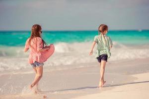 Little happy funny girls have a lot of fun at tropical beach playing together. photo