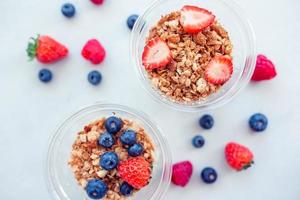 Oatmeal porridge in bowl topped with fresh blueberries, cranberries and homemade crunchy granola photo