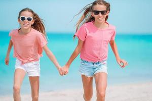 Little happy funny girls have a lot of fun at tropical beach playing together. photo