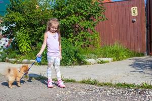 Little girl walking with her dog on a leash photo