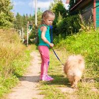 Little girl walking with her dog on a leash photo