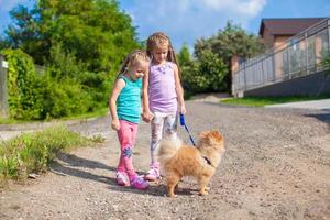 Two Little girls walking with small dog on a leash outdoor photo
