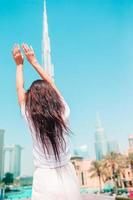 mujer feliz caminando en dubai con rascacielos en el fondo. vista desde atrás. foto