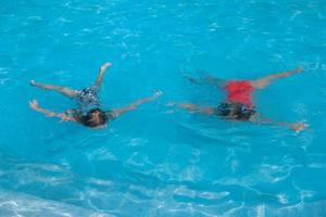 Little adorable girls swimming in the swimmingpool photo