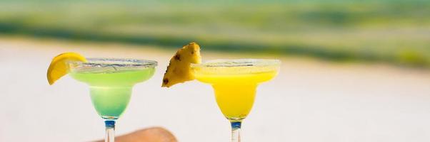 Two tasty alcoholic cocktails on background of turquoise sea photo