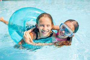 Adorable little sisters play in outdoor swimming pool photo