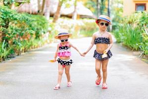 Little happy funny girls have a lot of fun at tropical beach playing together. photo