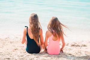 Little happy funny girls have a lot of fun at tropical beach playing together. photo