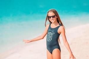 Adorable little girl have fun at tropical beach during vacation photo