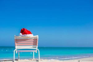 Red Santa hat on chair longue at sea shore photo