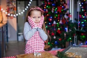 adorable niñita con mitones para hornear galletas de jengibre navideñas foto