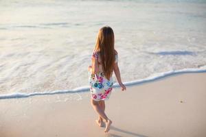 adorable niña caminando en la playa tropical blanca foto