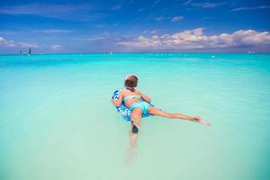 Little girl swimming on a surfboard in the turquoise sea photo