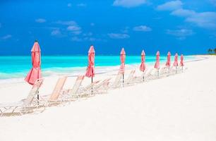 Paradise view of tropical empty sandy plage with umbrella and beach chair photo