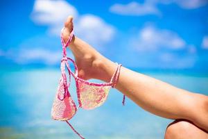 Pink swimsuit on female leg on white tropical beach photo