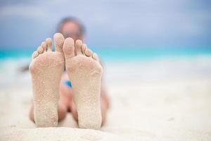 cerca de pies femeninos en la playa de arena blanca foto