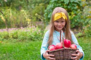 Portrait of little beautiful girl with basket of red apples photo