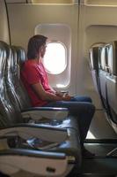 Young man looking in window on board of an airplane during the flight photo